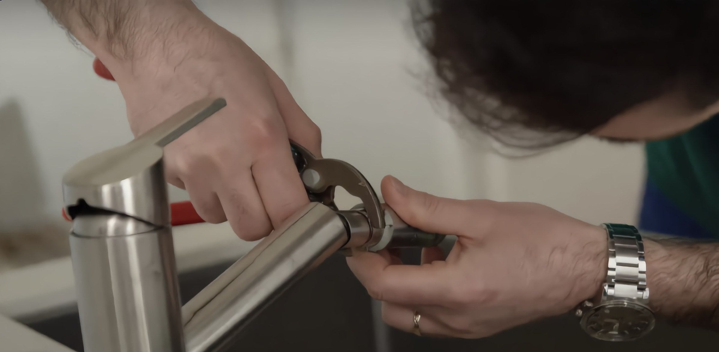 Installation d’un raccord sur une arrivée d’eau, mains d’un plombier au travail